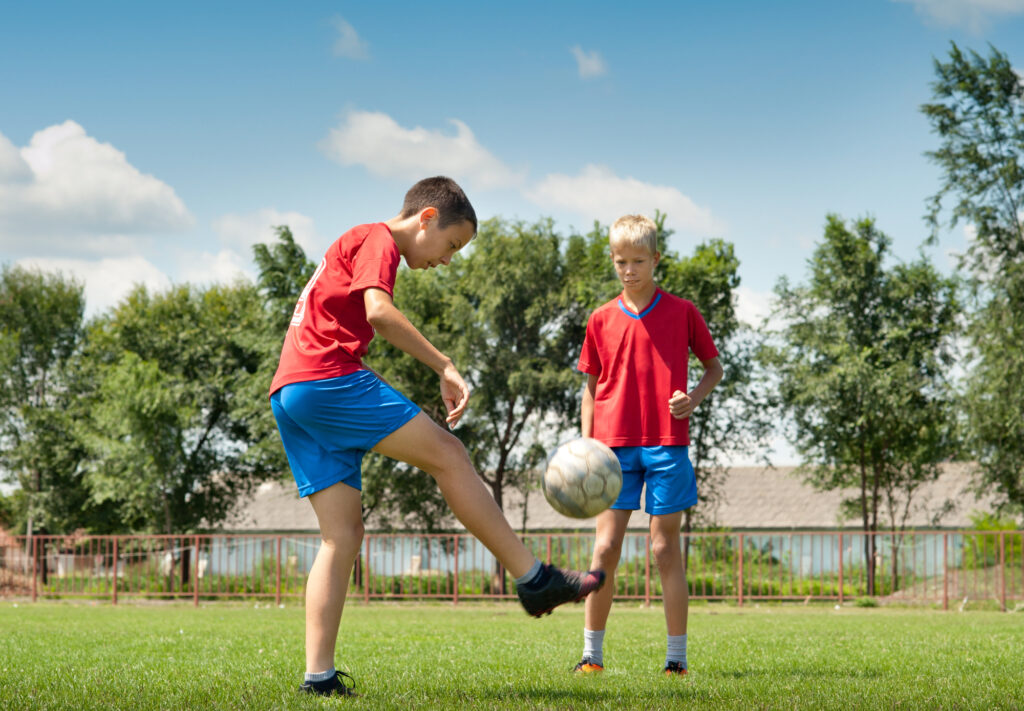 2 boys juggling a soccer ball